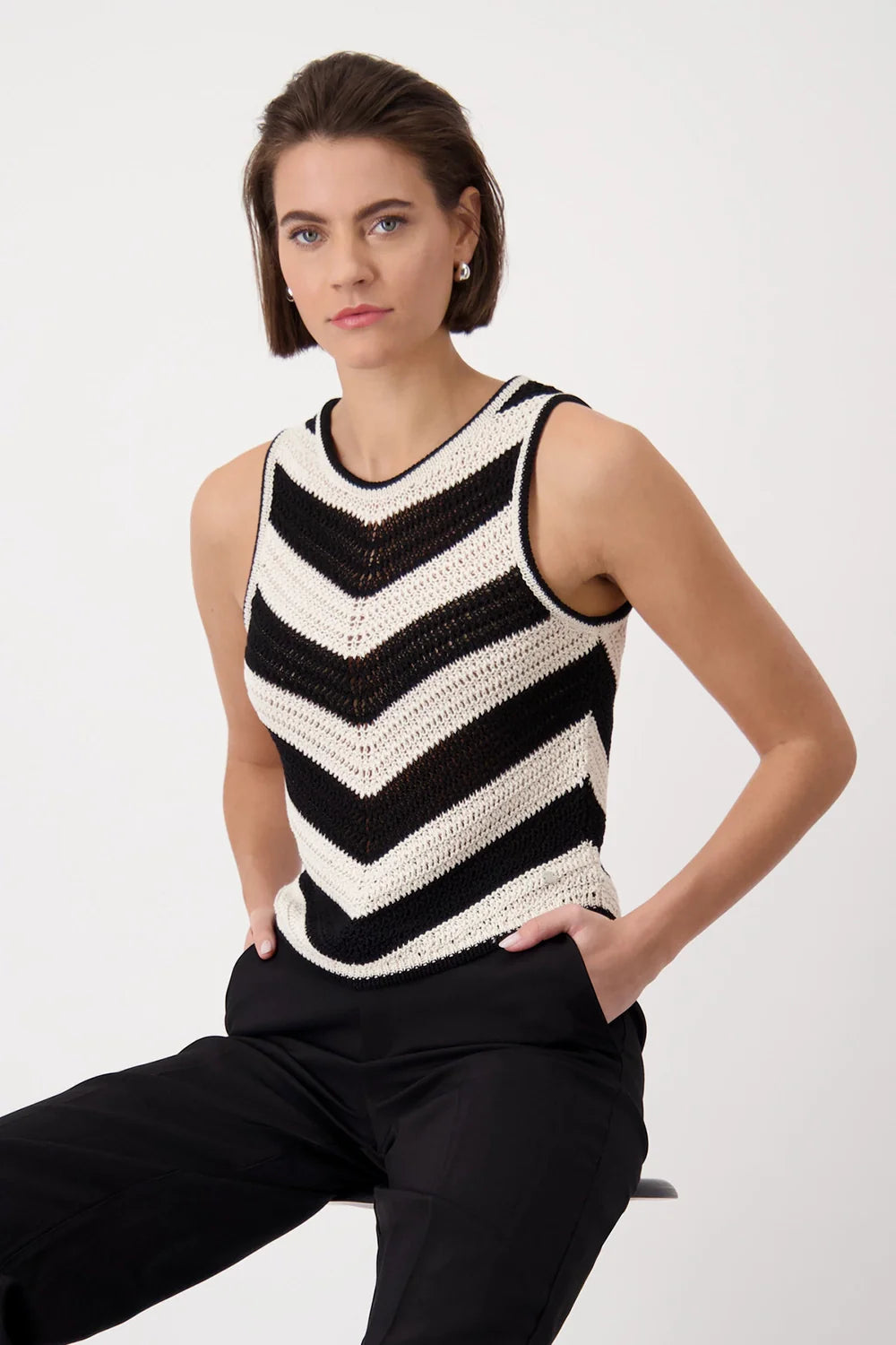 Woman wearing a black and white striped sleeveless sweater against a white background