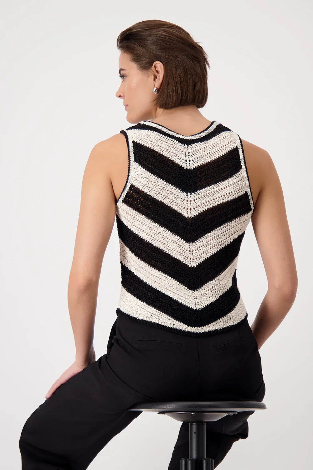 Woman wearing a black and white striped sleeveless crochet top on a white background