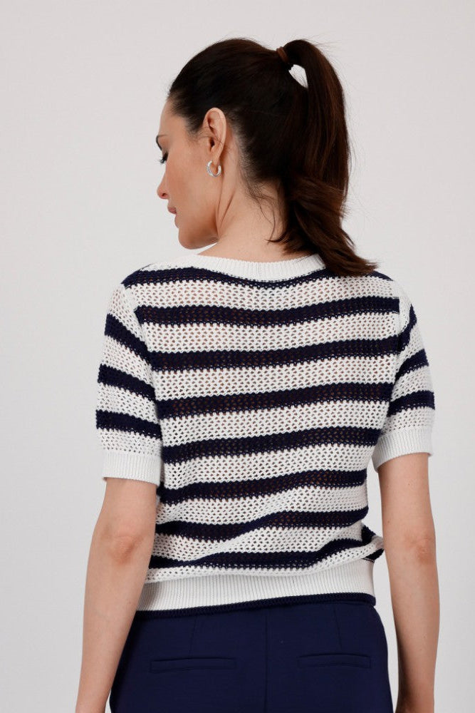 Woman wearing a navy and white striped short sleeve knit top with navy pants on a plain background
