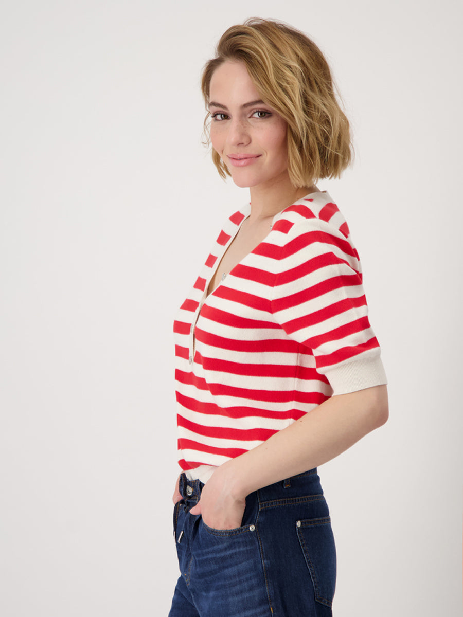 Woman wearing a red and white striped shirt with blue jeans on a plain background