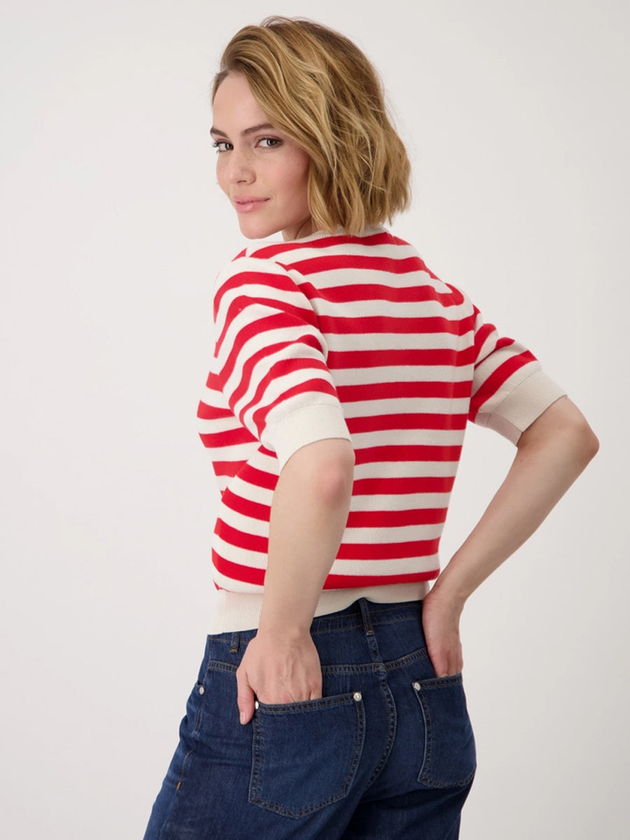 Woman wearing a red and white striped shirt with blue jeans on a plain background