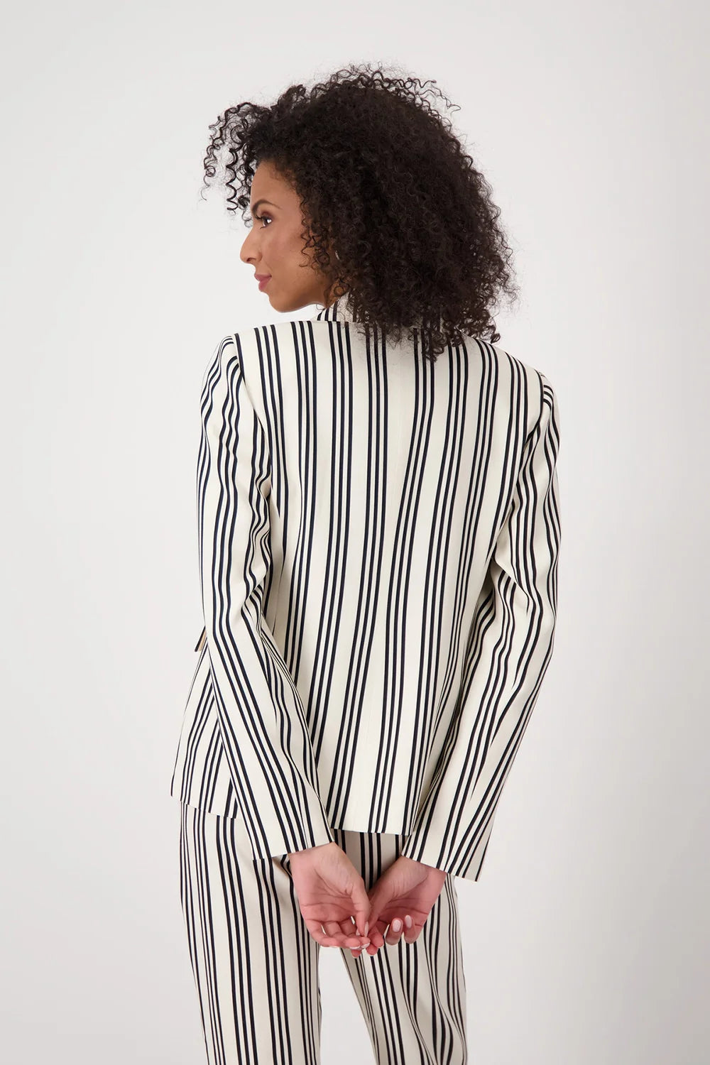Woman wearing a black and white striped suit against a plain background