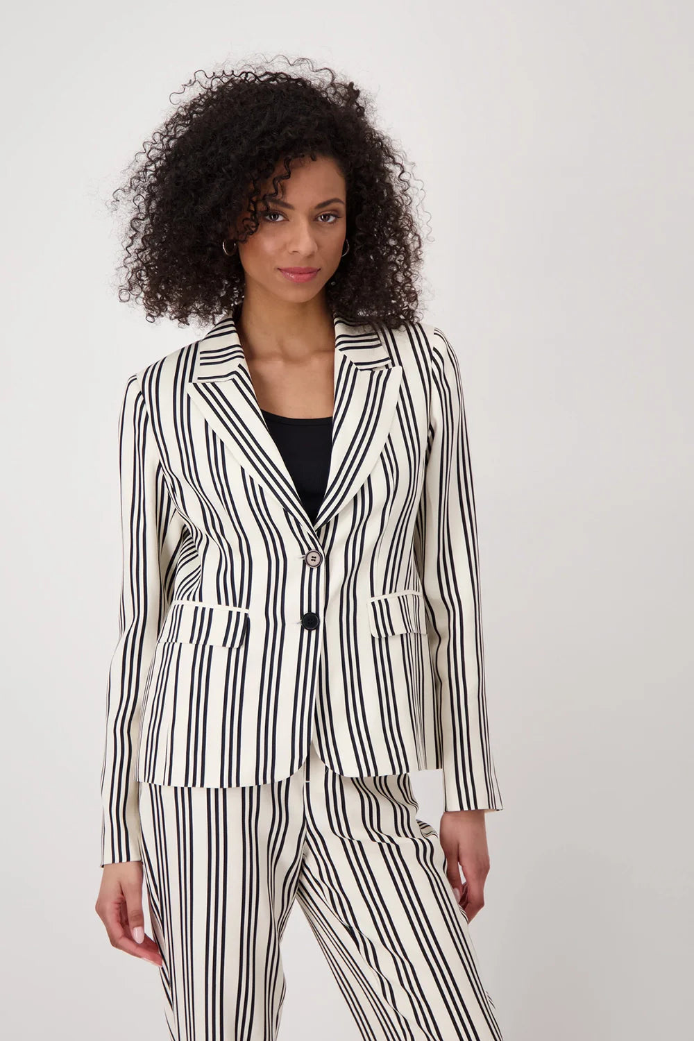 Woman wearing a black and white striped suit against a plain background