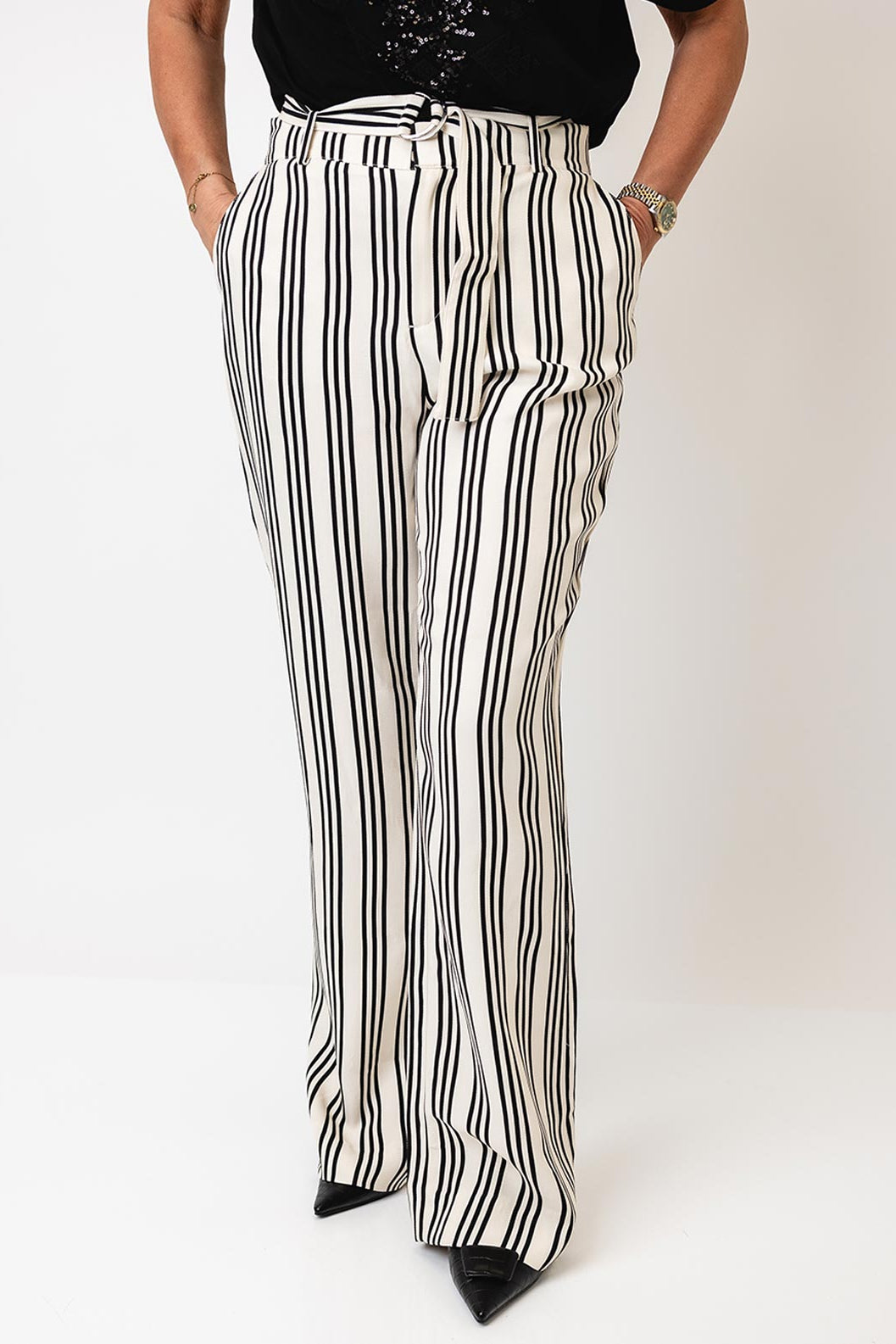 Model wearing black and white striped pants on a plain background