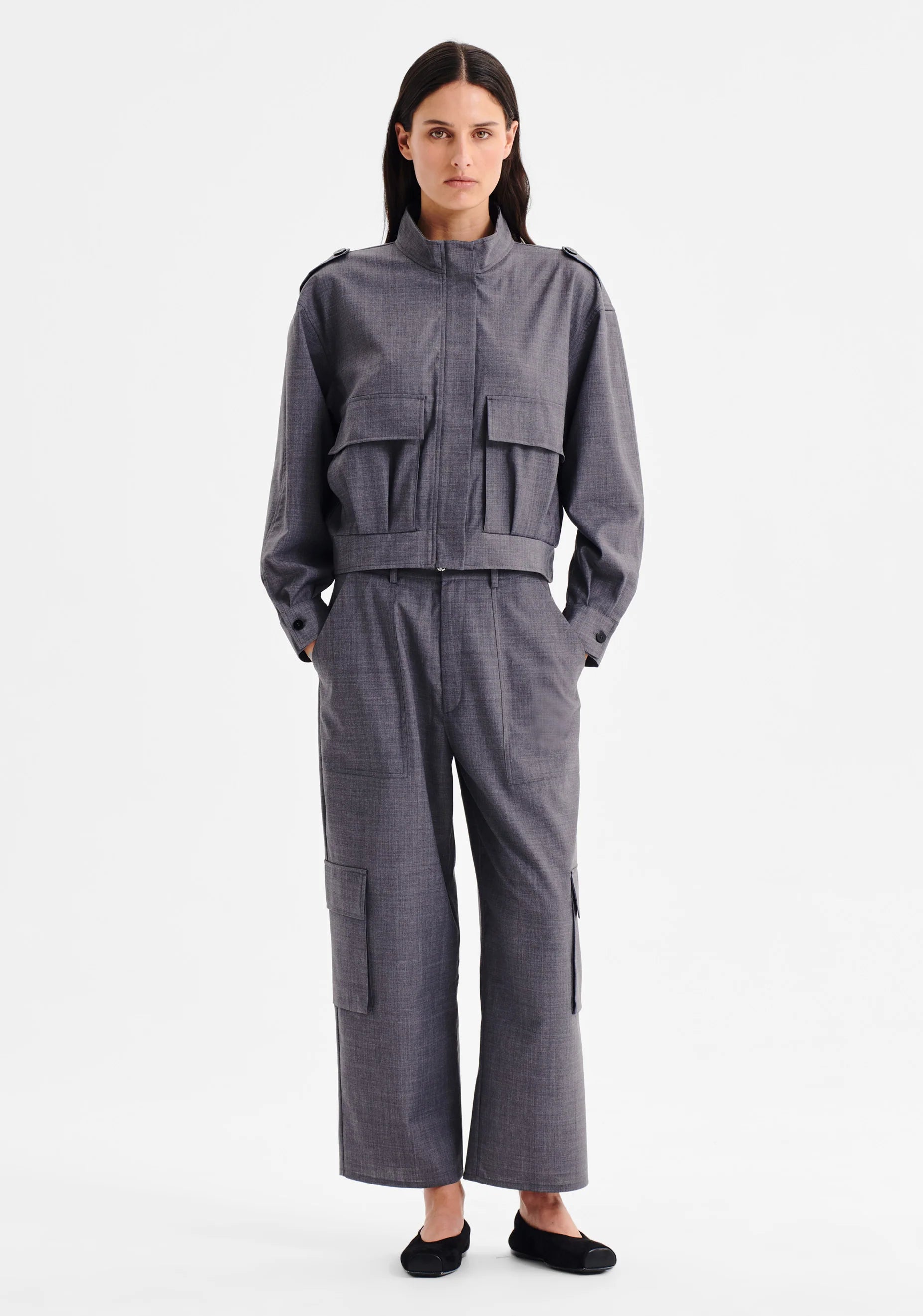 Women wearing charcoal grey cropped cargo pants and matching top on a white background. 
