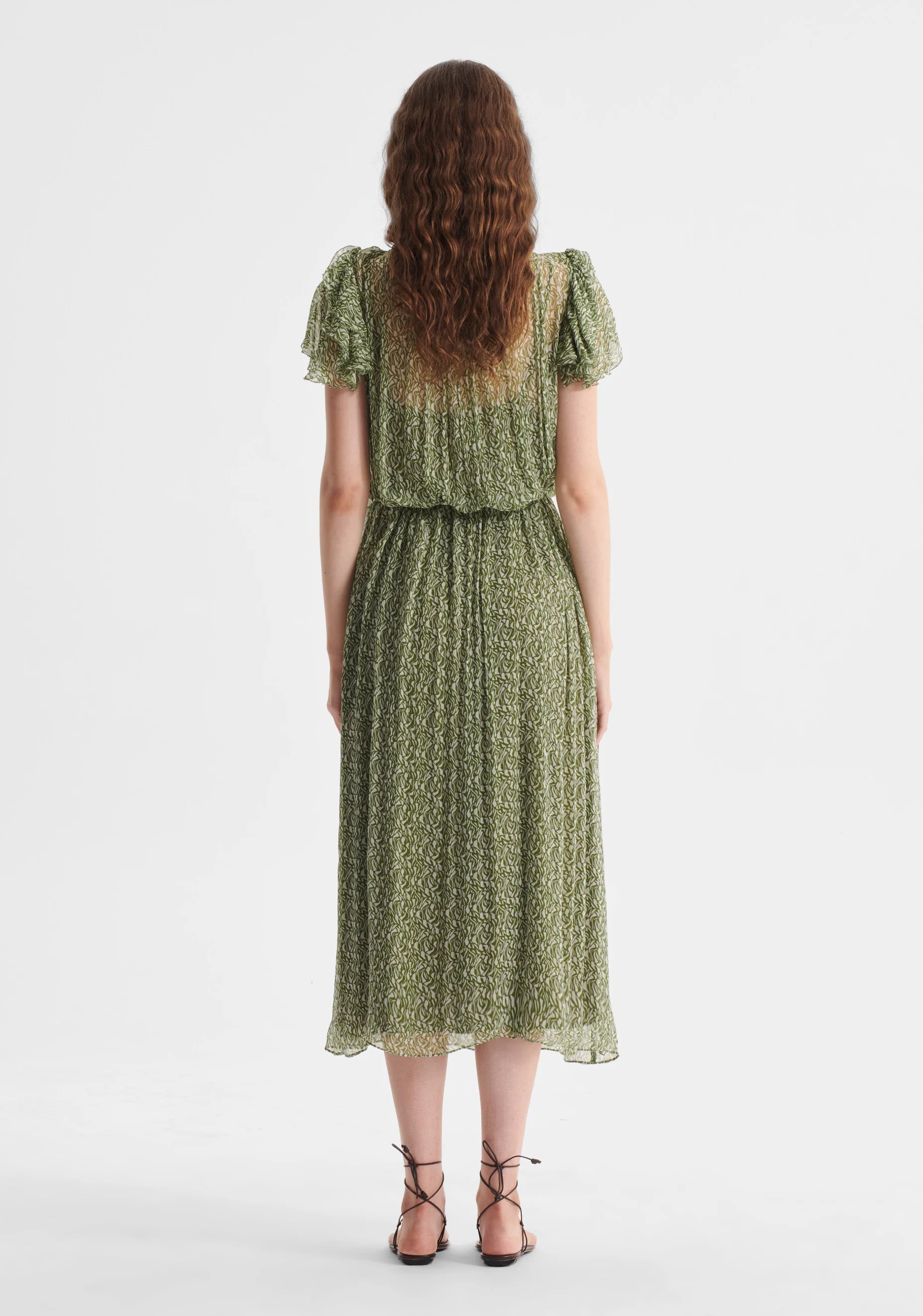 Woman wearing a green floral dress on a white background