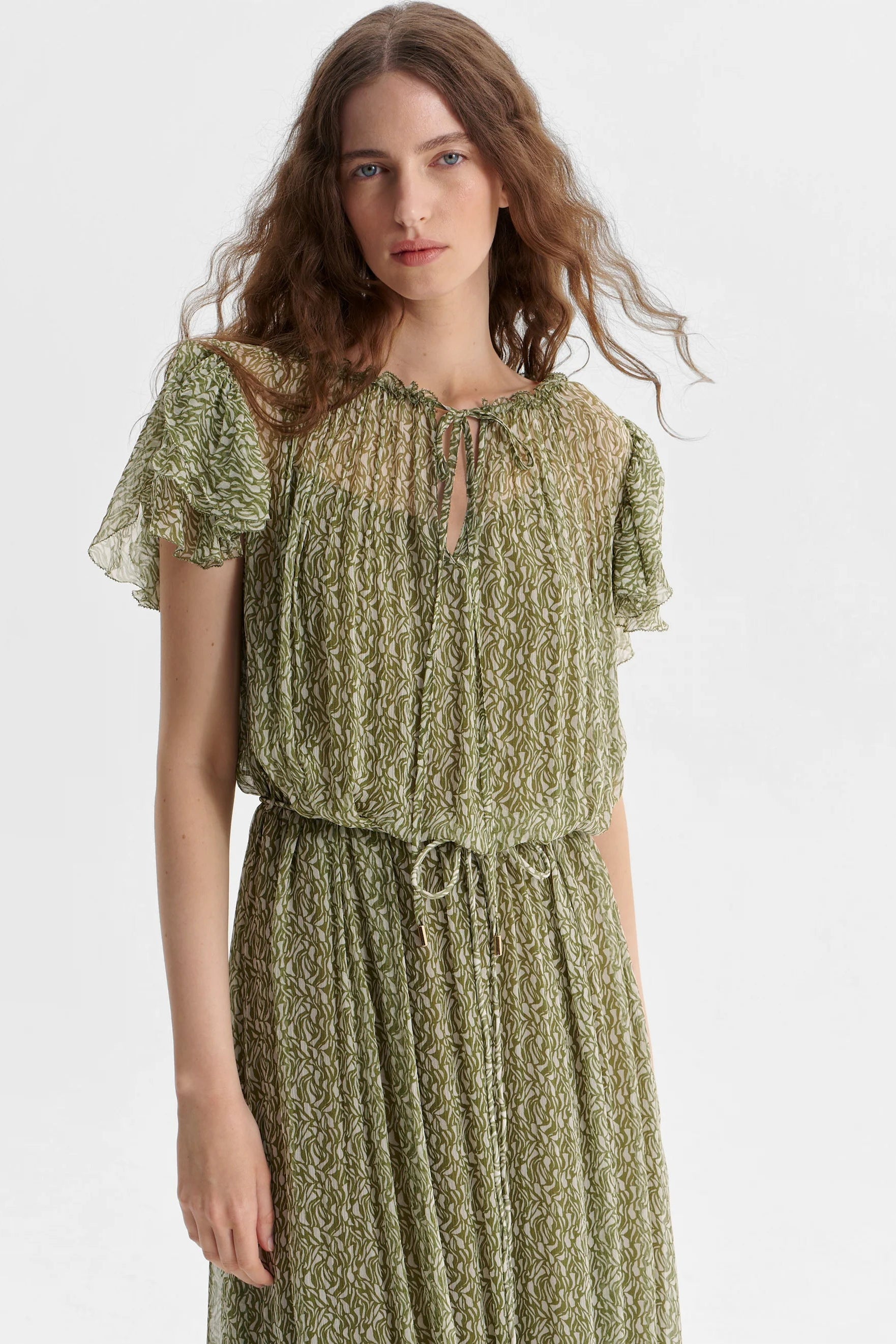 Woman wearing a green dress with a textured pattern on a white background