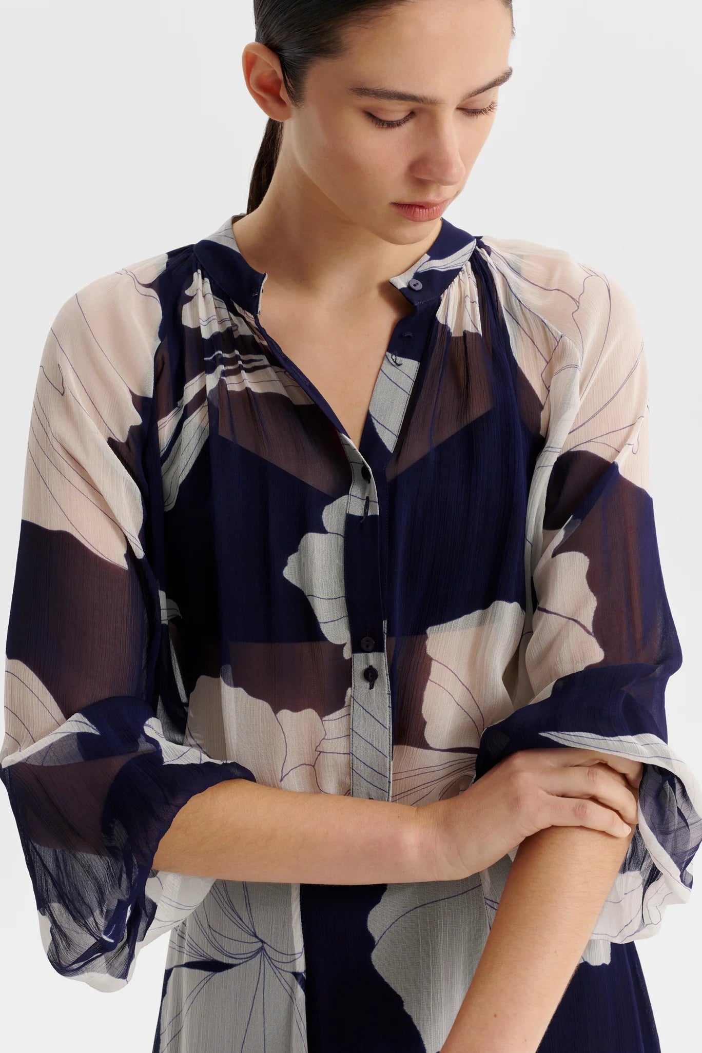 Woman wearing a blue and white patterned blouse with a neutral background