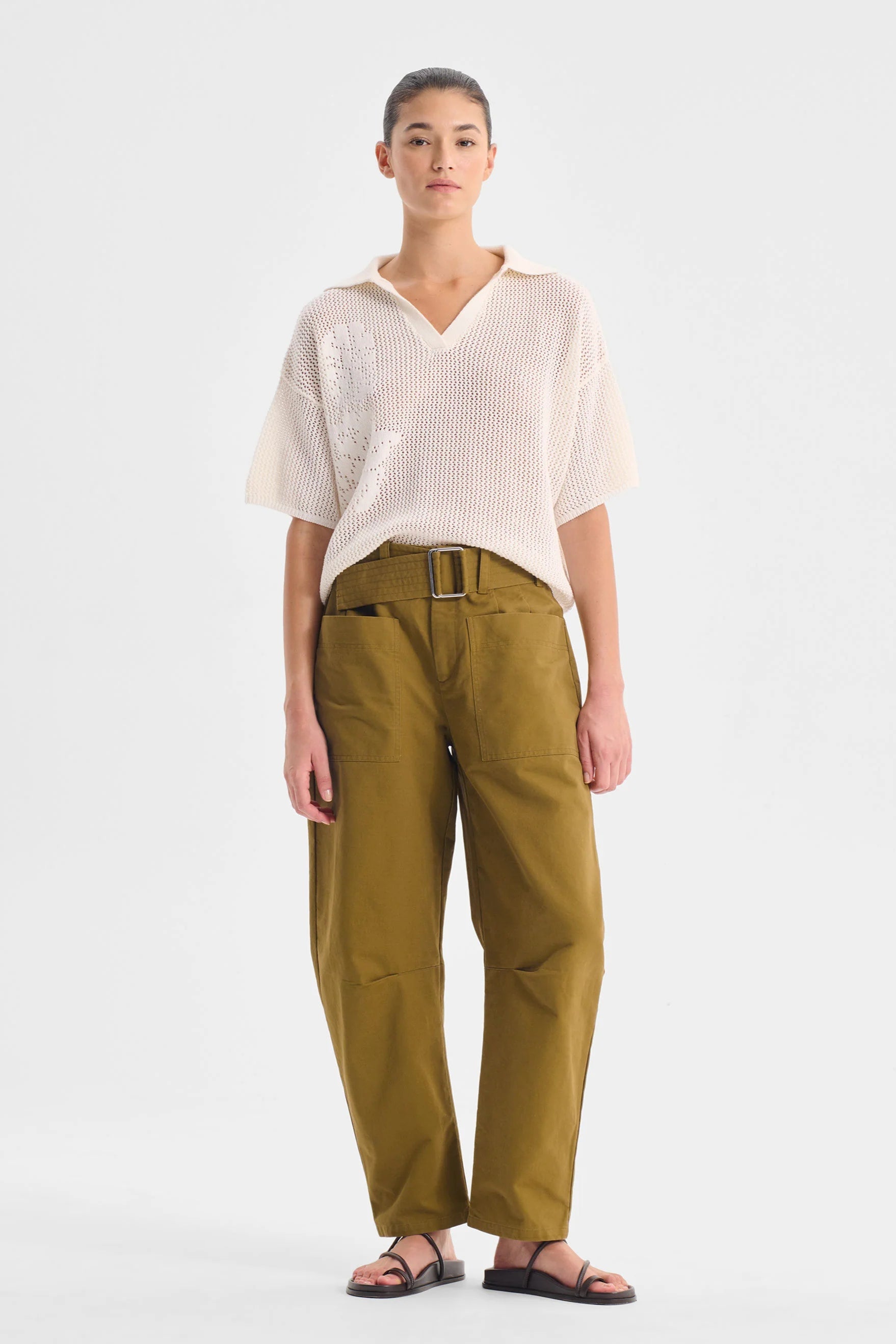 Woman wearing a white top and mustard yellow pants on a white background