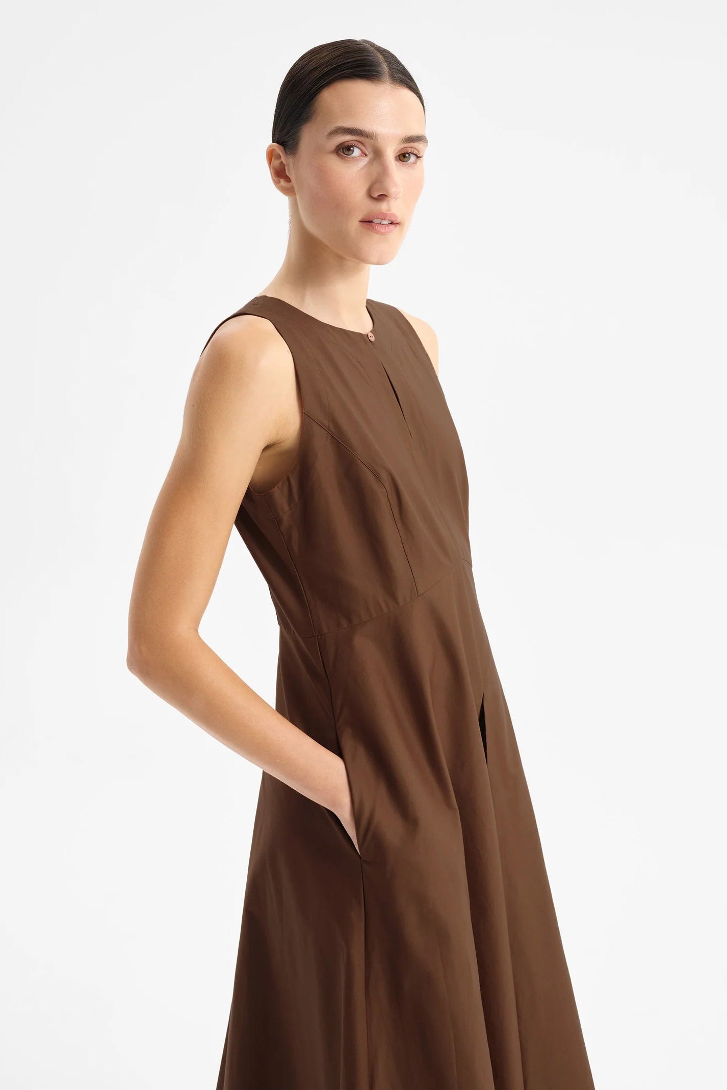Model wearing sleeveless chocolate brown midi length dress with fitted bodice and full skirt.  
