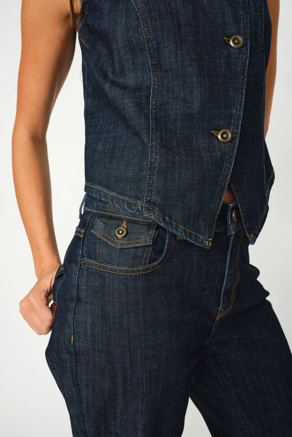 Close-up of a person wearing a dark blue denim vest and pants on a white background