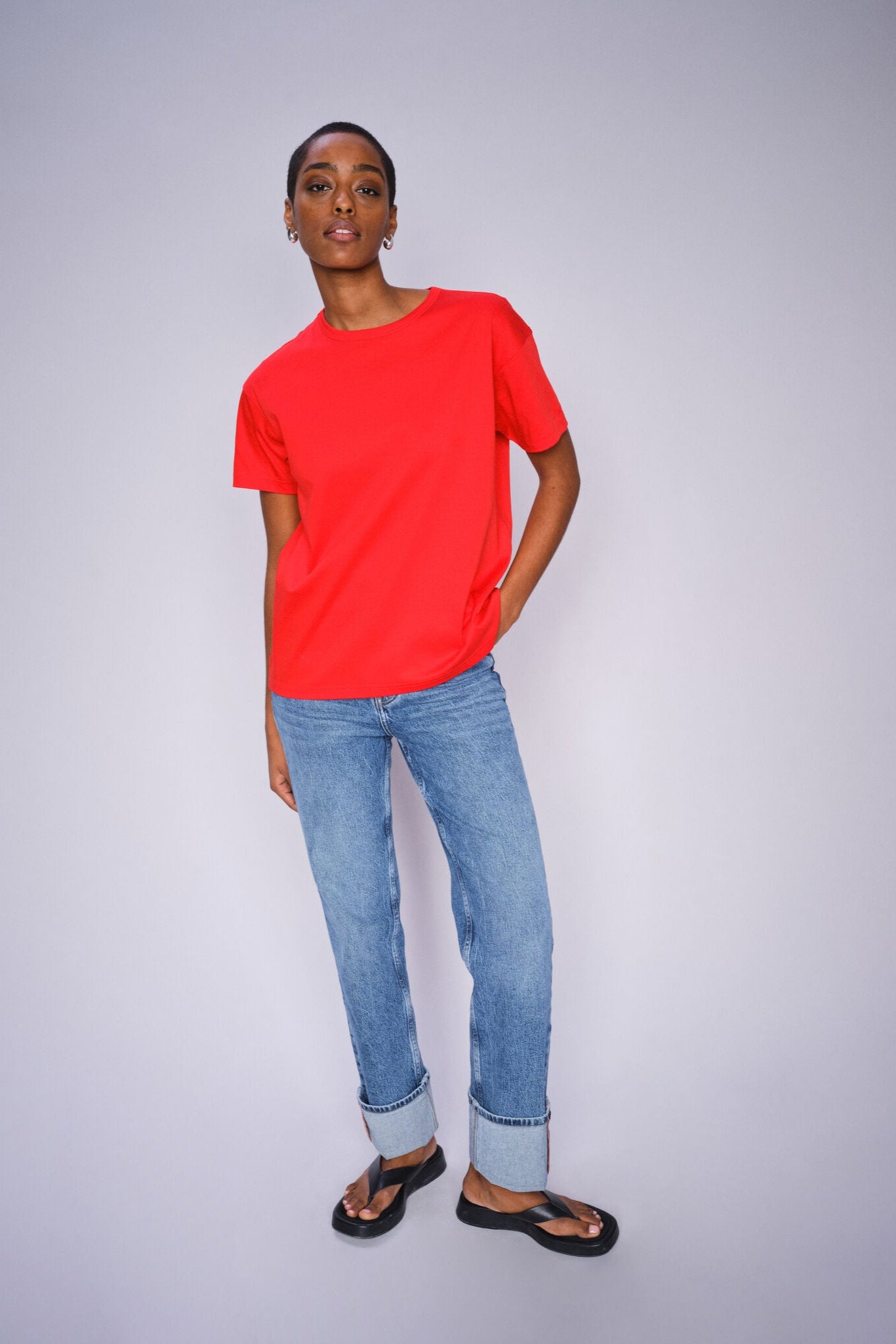 Model wearing Chinese Red o neck t-shirt  paired with denim jeans and black sandals. 