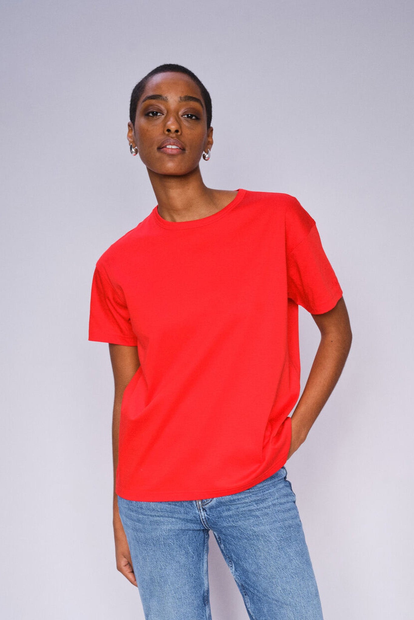 Model wearing Chinese Red o neck t-shirt  paired with denim jeans on a grey background 