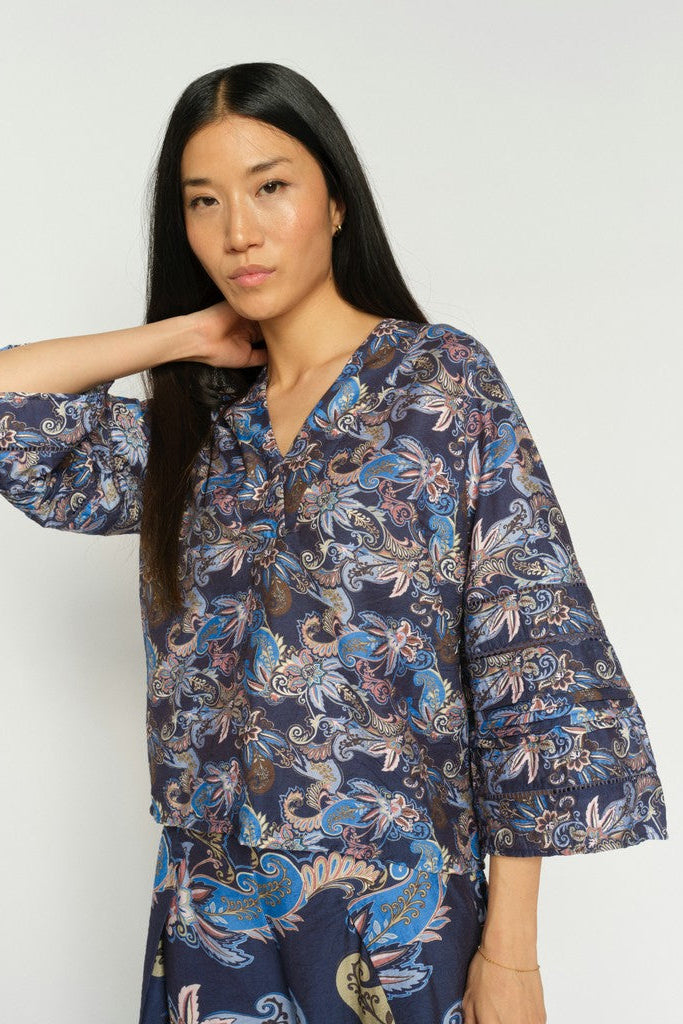 Women wearing 3/4 sleeve v neck Paisley blue print blouse and matching pants on a white background. 