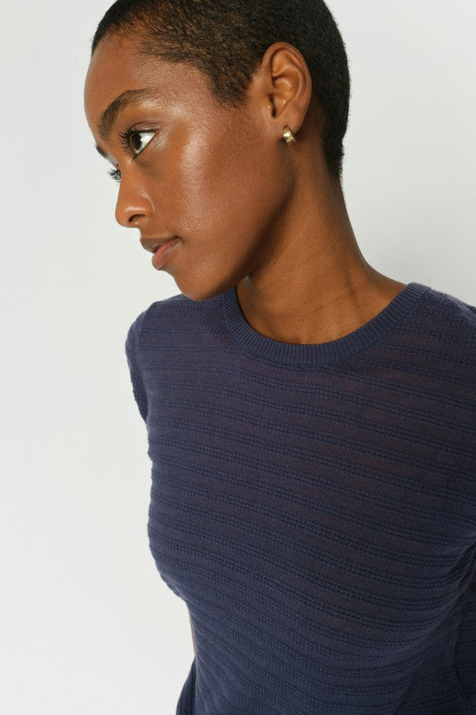 Side profile of model wearing a Blue short sleeve textured sweater with round neck on a white background