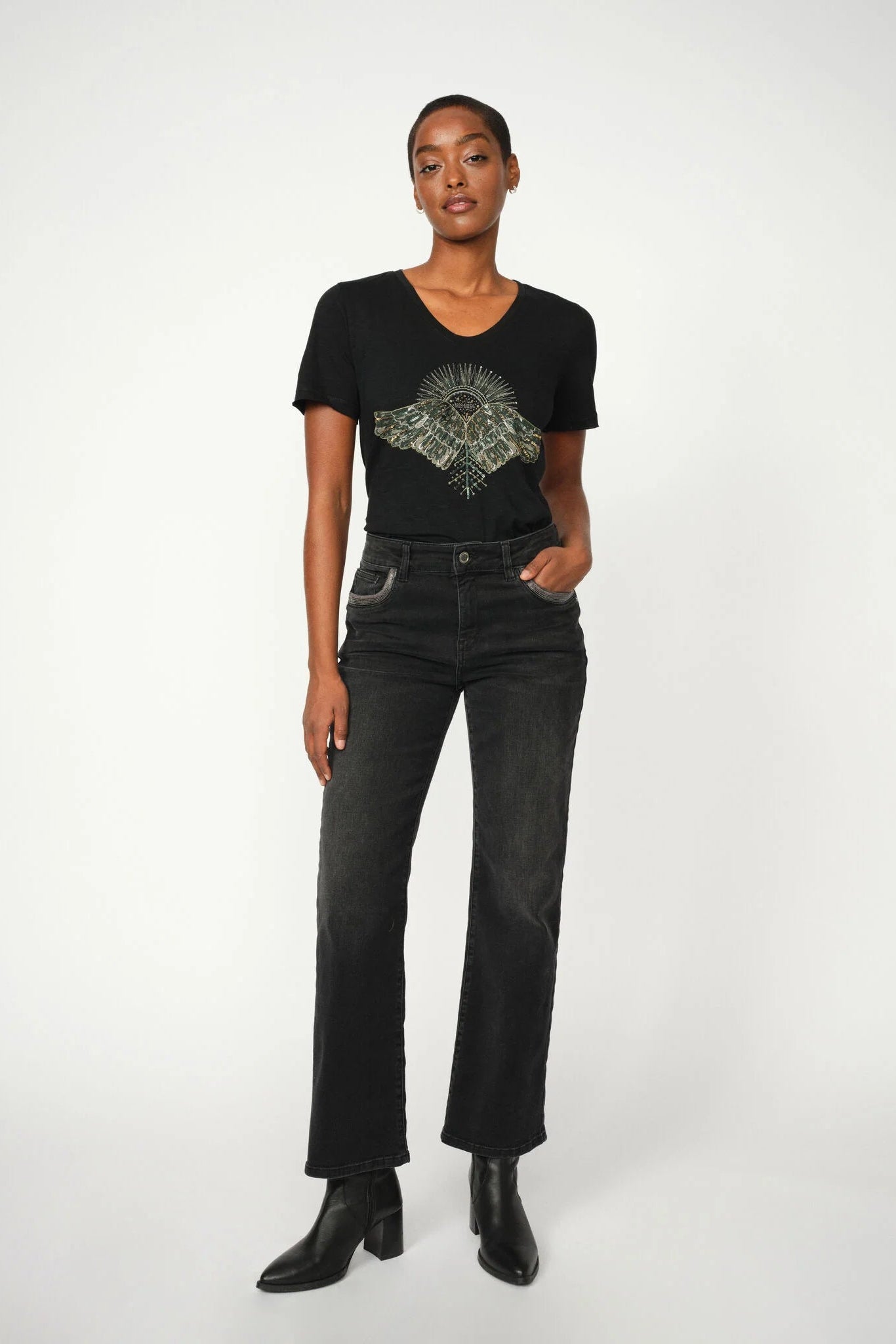 Person wearing a black t-shirt with a graphic design and black jeans on a white background