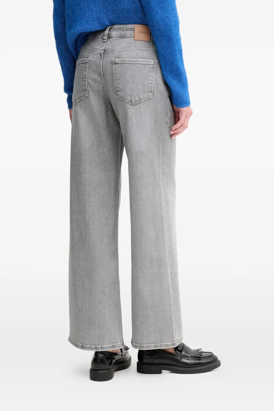 Person wearing gray wide-leg jeans and a blue sweater on a white background