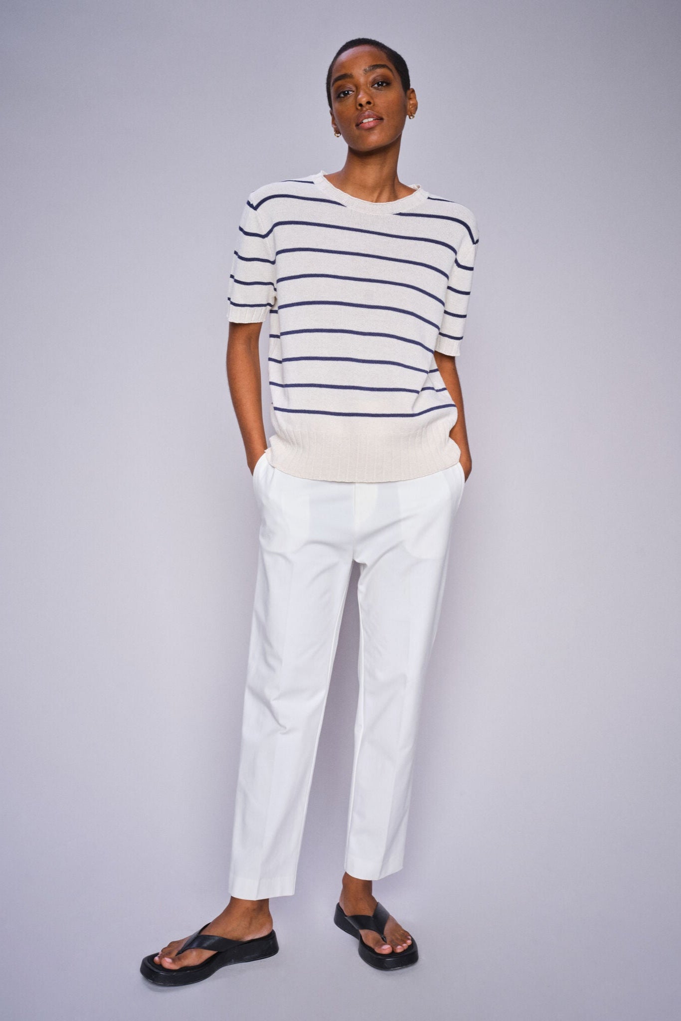Model wearing white and blue strip short sleeve knit top and white cropped pants with sandals.  