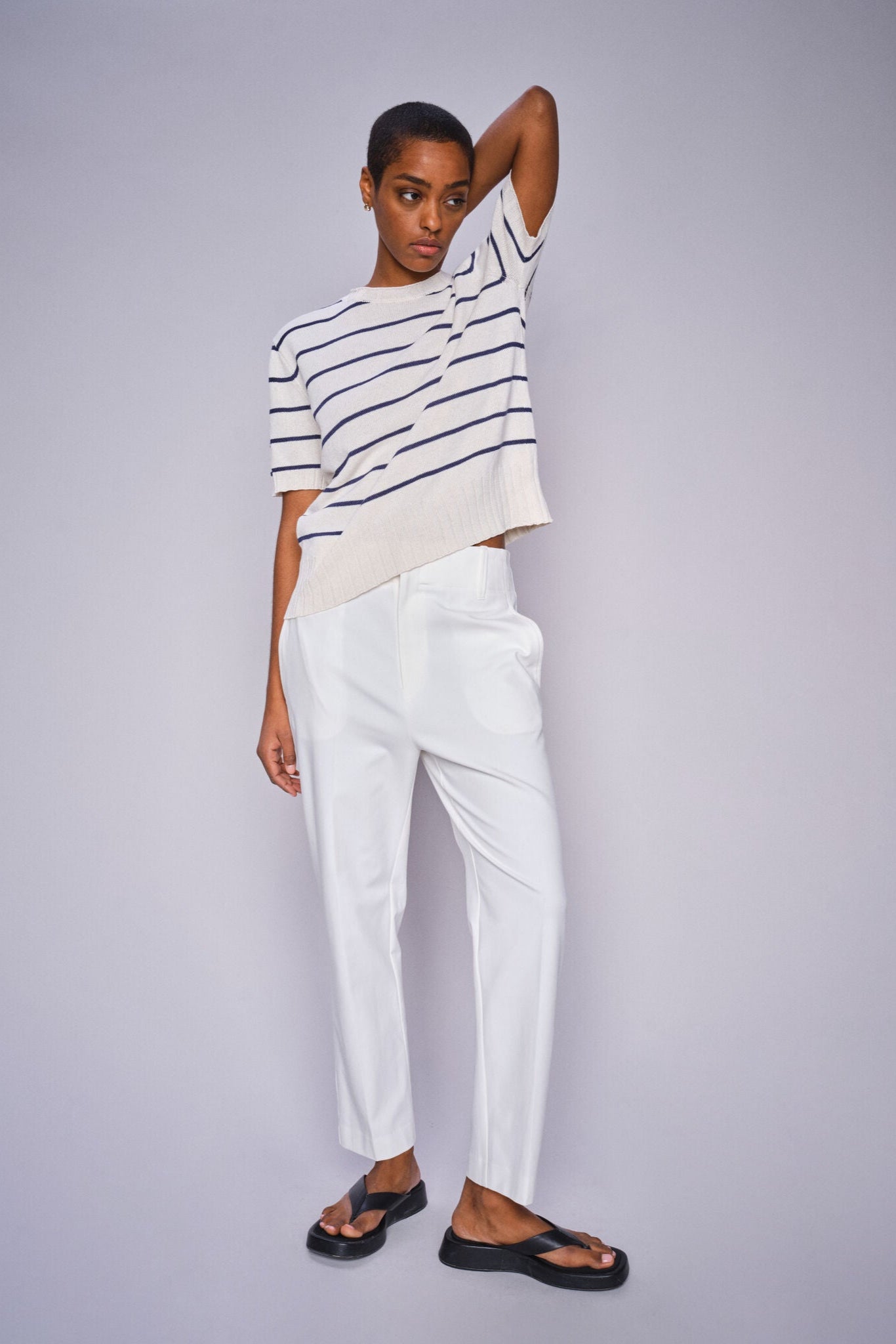 Model wearing white and blue strip short sleeve knit top and white cropped pants with sandals.  