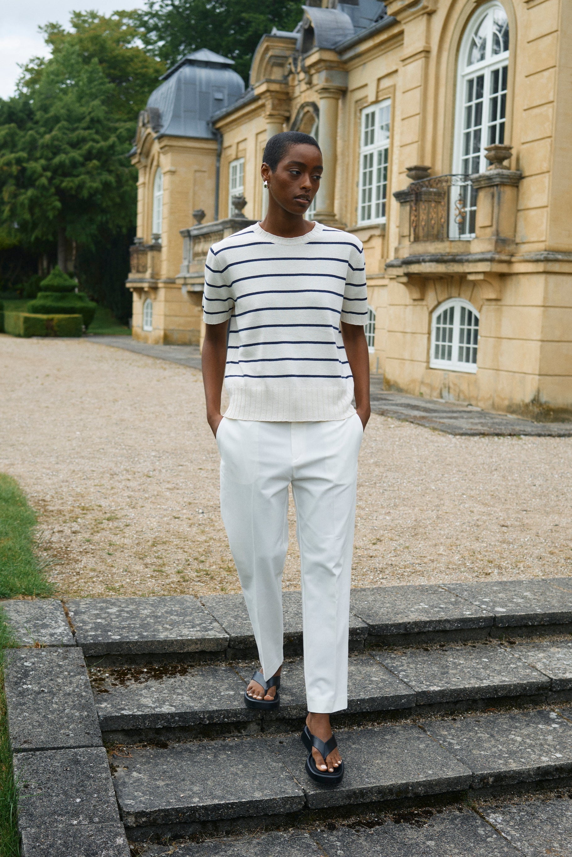 Model wearing white and blue strip short sleeve knit top and white cropped pants with sandals.  