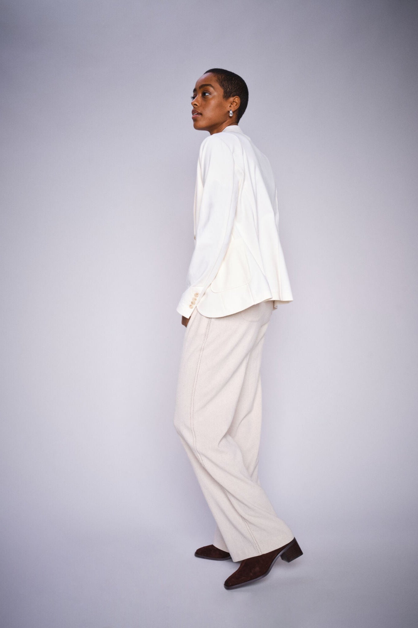 Model wearing beige straight leg pants with elastic waist band and draw string and a white blazer and brown boots on a white background