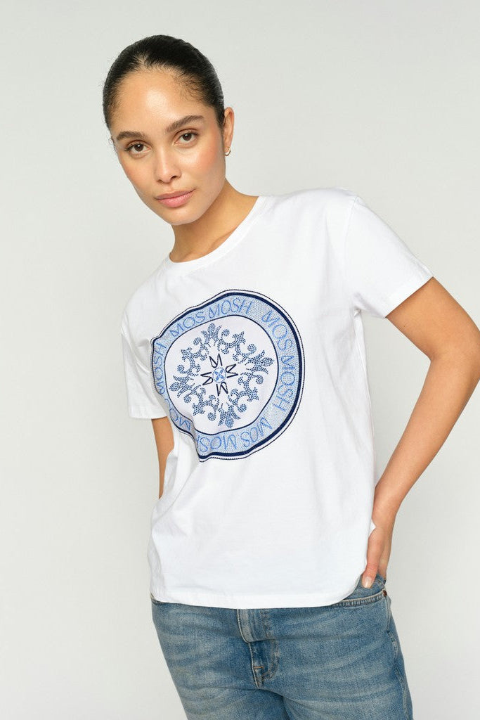 Woman wearing a white t-shirt with a blue circular design on a plain background
