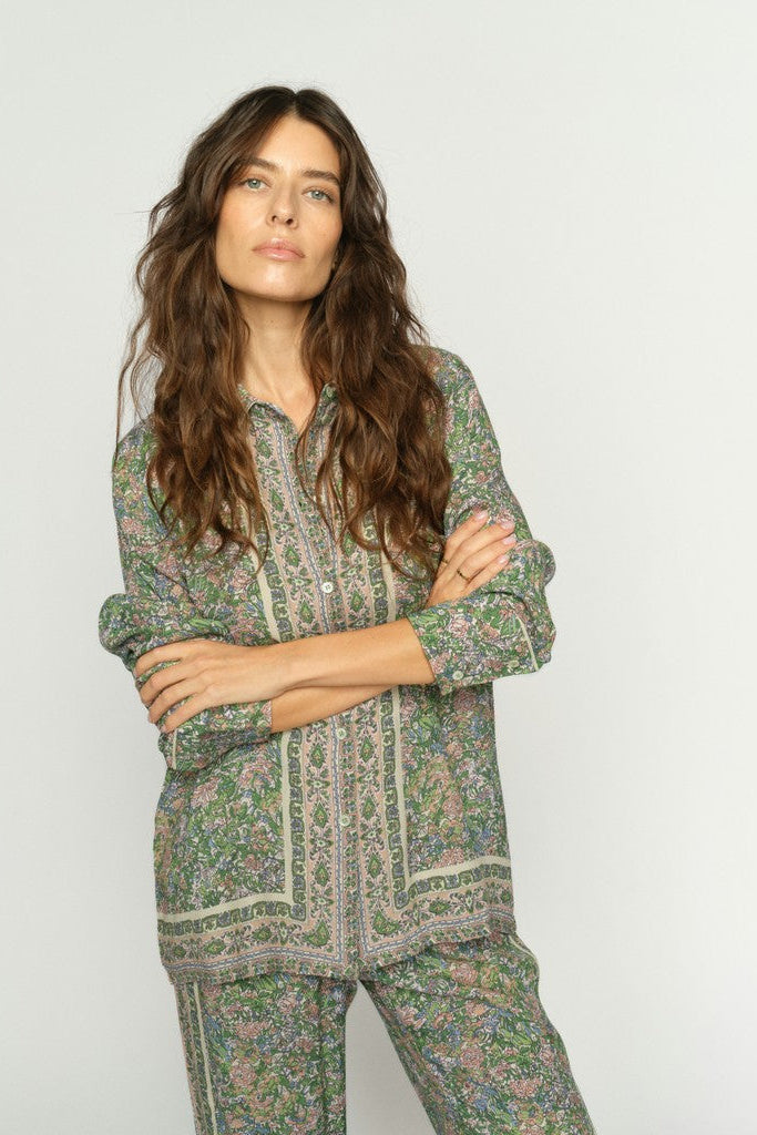 Woman wearing a green floral patterned shirt and matching pants against a plain background