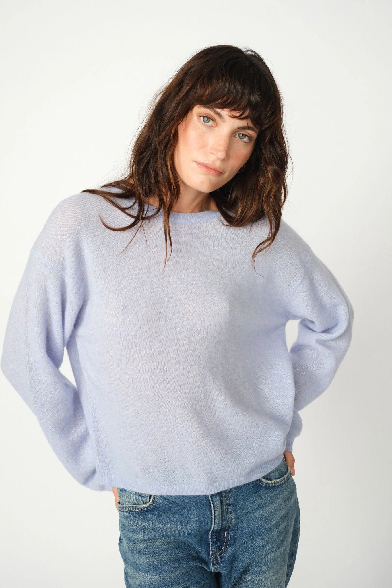 Woman wearing a light blue sweater and jeans on a white background