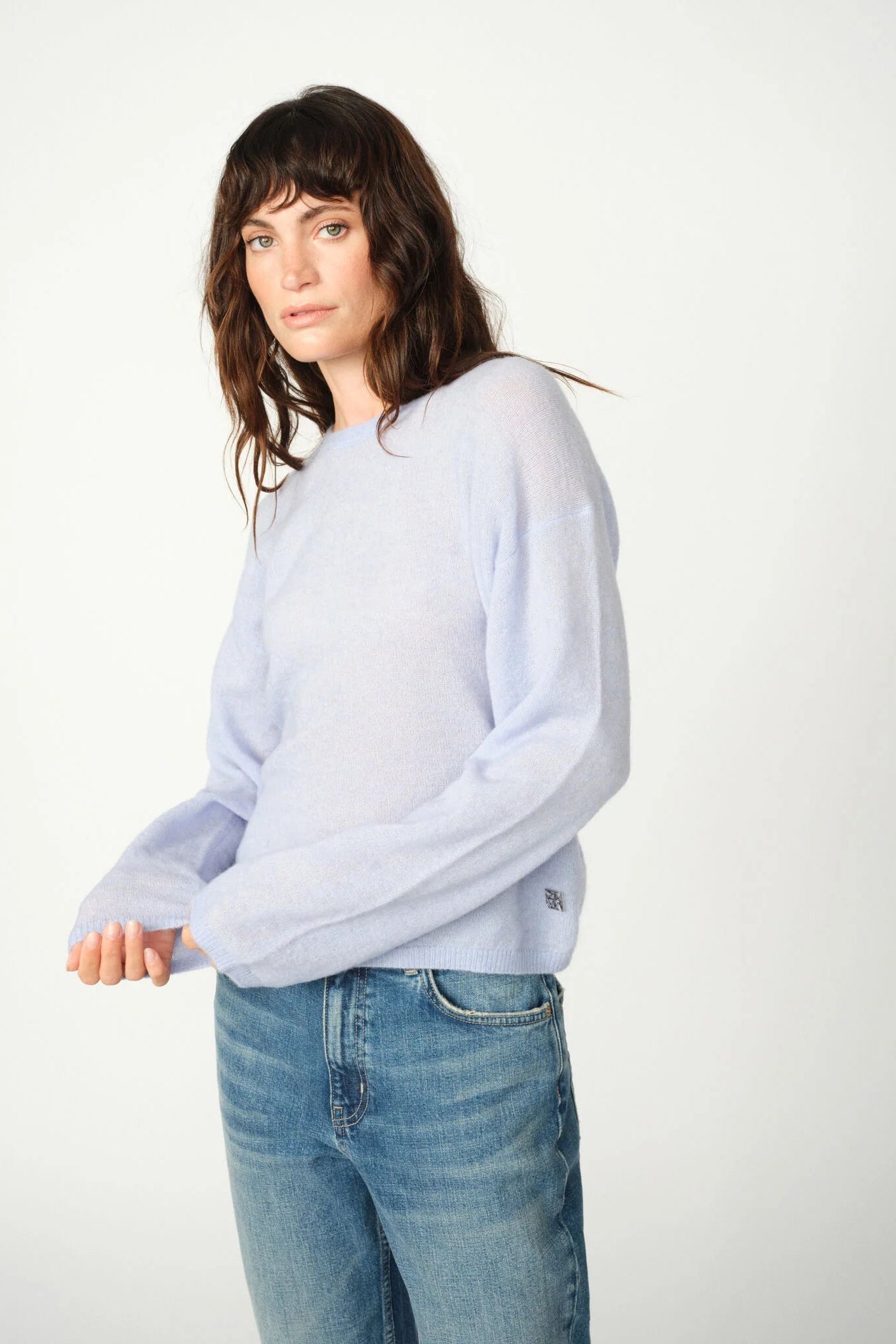 Woman wearing a light blue sweater and jeans on a white background