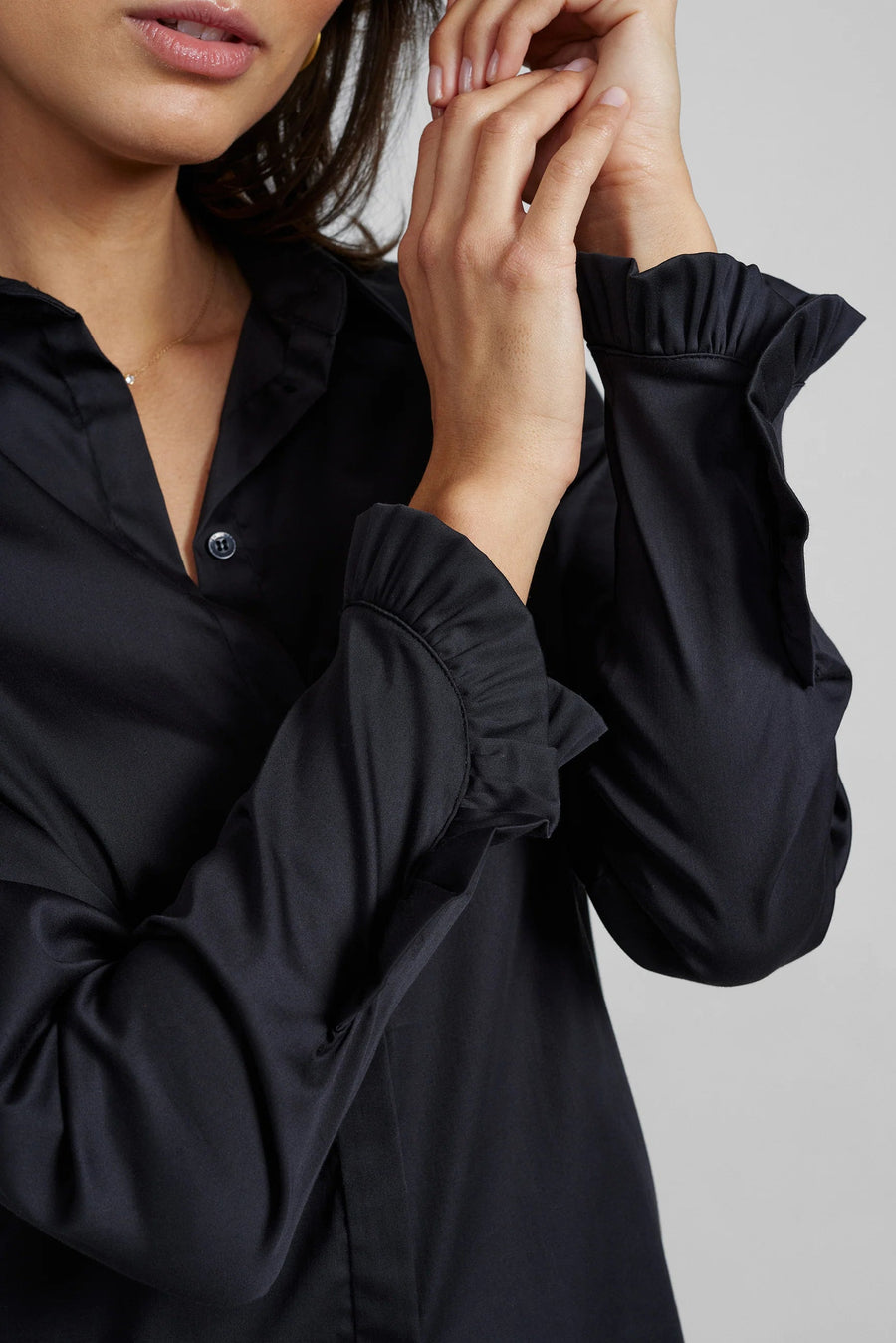 Black long sleeve shirt with frill detail on the cuff close up. 