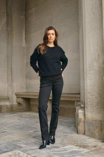 Black tapered jean with mid rise and zip detail at left front pocket. 