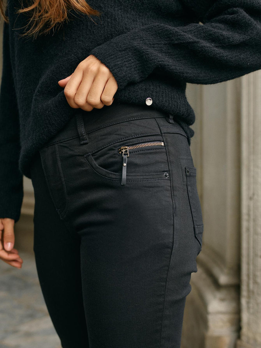 Black tapered jean with mid rise and zip detail at left front pocket. 