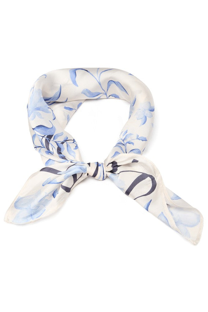 A square scarf tied featuring a light blue floral pattern on a white background, with 'MOS MOS' printed in dark blue along the borders