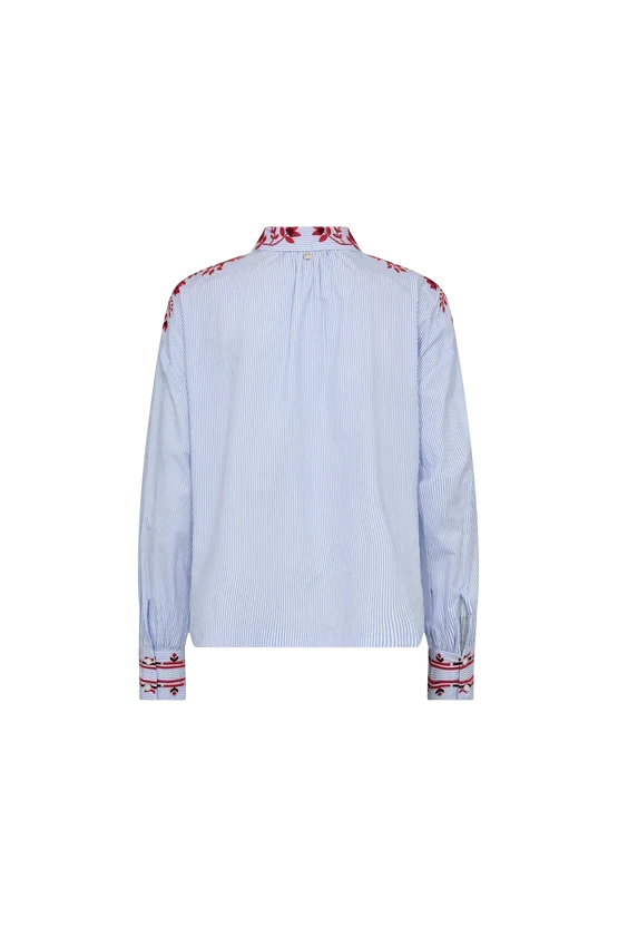 A light blue long-sleeve button-up shirt shown from the back, featuring red and white embroidered patterns on the collar, shoulders, and cuffs.