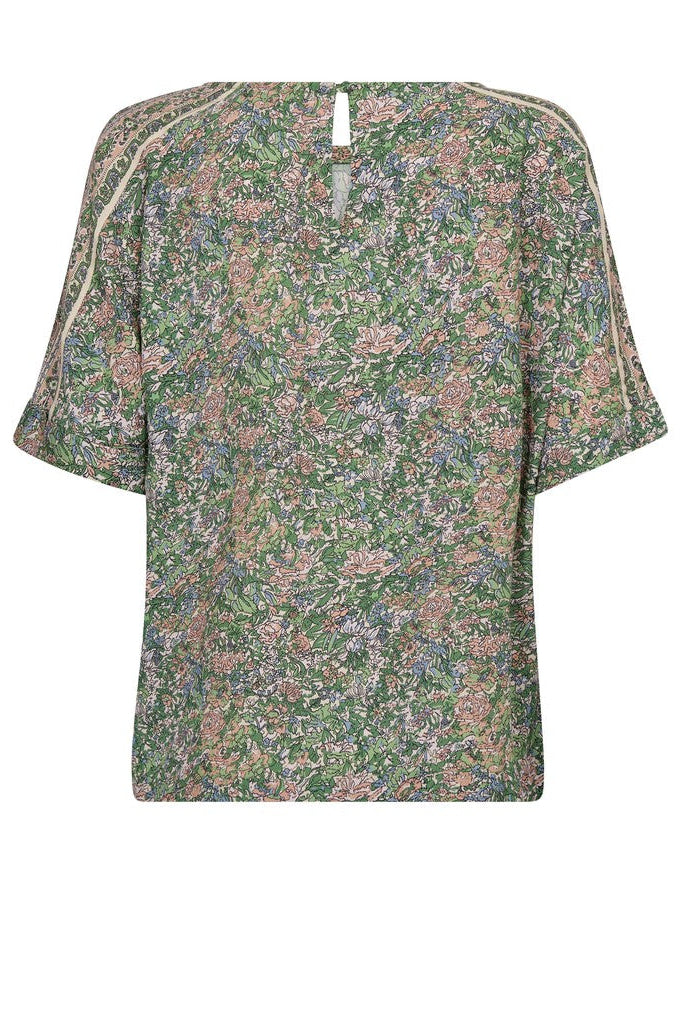 A short-sleeve top with an all-over dense floral print in green, pink, and beige tones, featuring contrasting light beige piping along the shoulder seams and neckline. Shown on a plain background. 