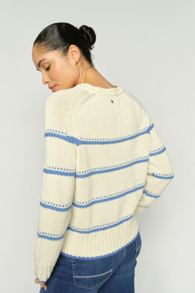 Woman shown from the back wearing a shite sweater with blue stripes and blue denim jeans on a white background