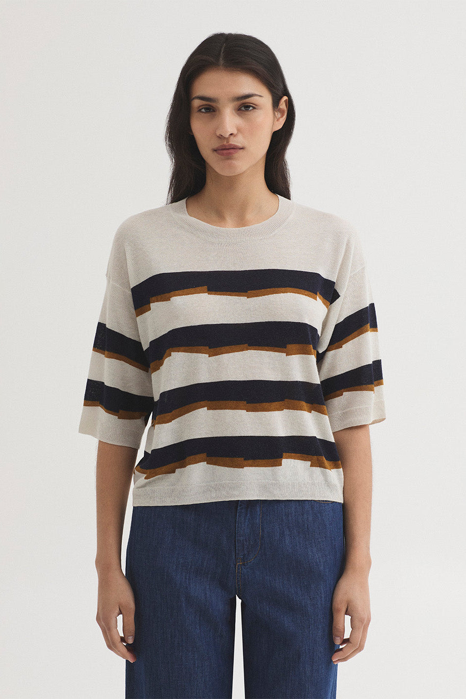 Woman wearing a striped sweater and blue pants on a white background
