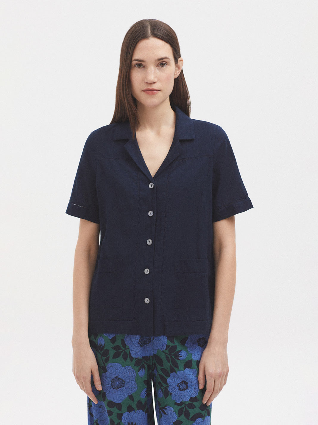 Model wearing a navy blue short-sleeve shirt with floral pants on a white background