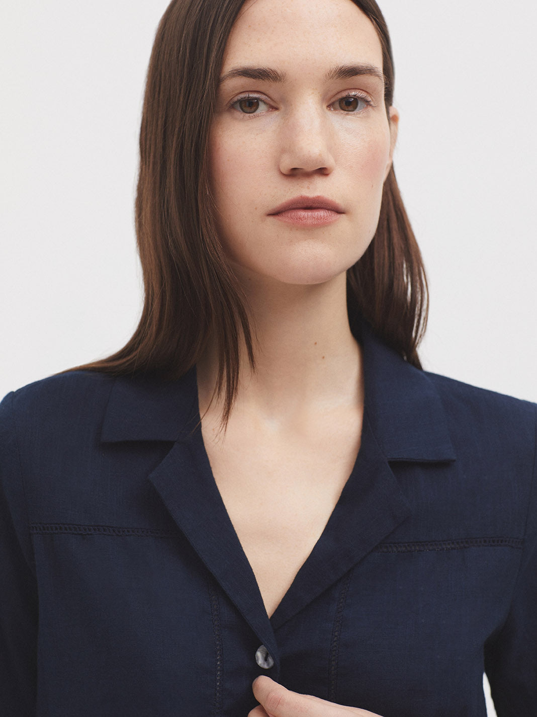 Model wearing a navy blue short-sleeve shirt with floral pants on a white background
