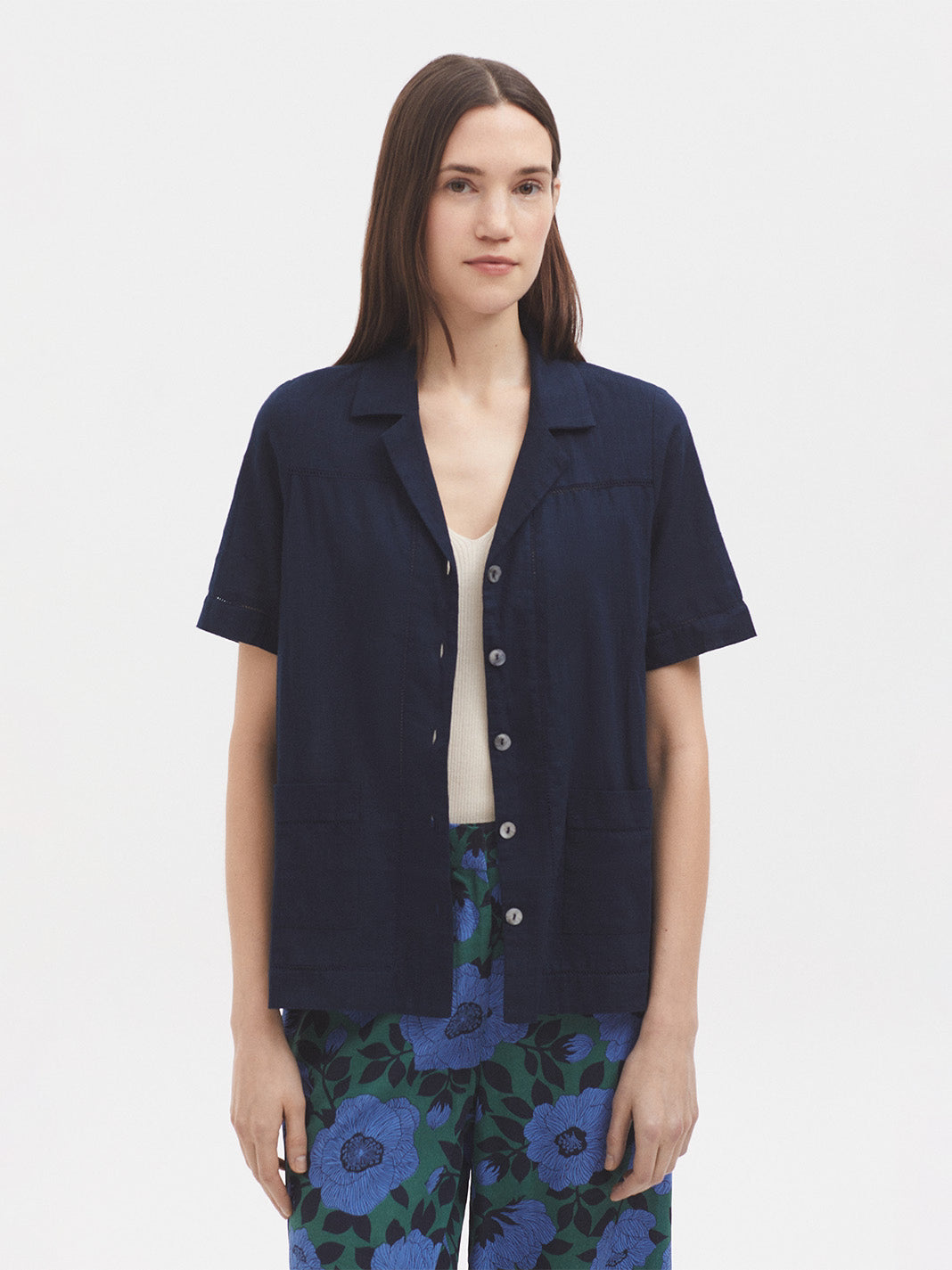Model wearing a navy blue short-sleeve shirt with floral pants on a white background
