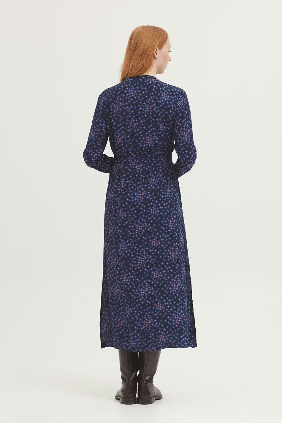 Woman wearing a long blue dress with a subtle pattern on a white background