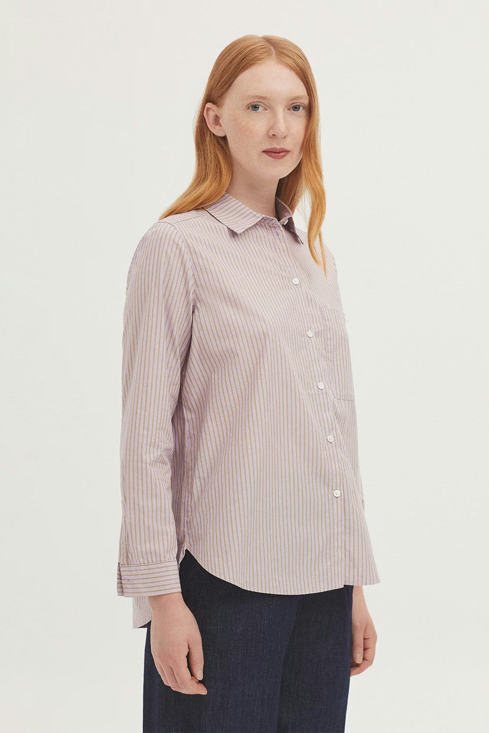 Woman wearing a striped lilac and green long sleeve shirt on a white background
