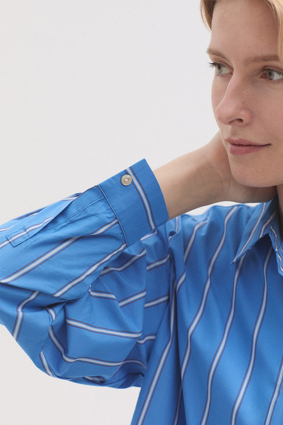Woman wearing a blue striped shirt against a light gray background