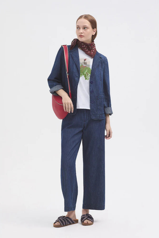 Model wearing wide leg denim jean with t shirt and denim over shirt with sandals and a red bag. 
