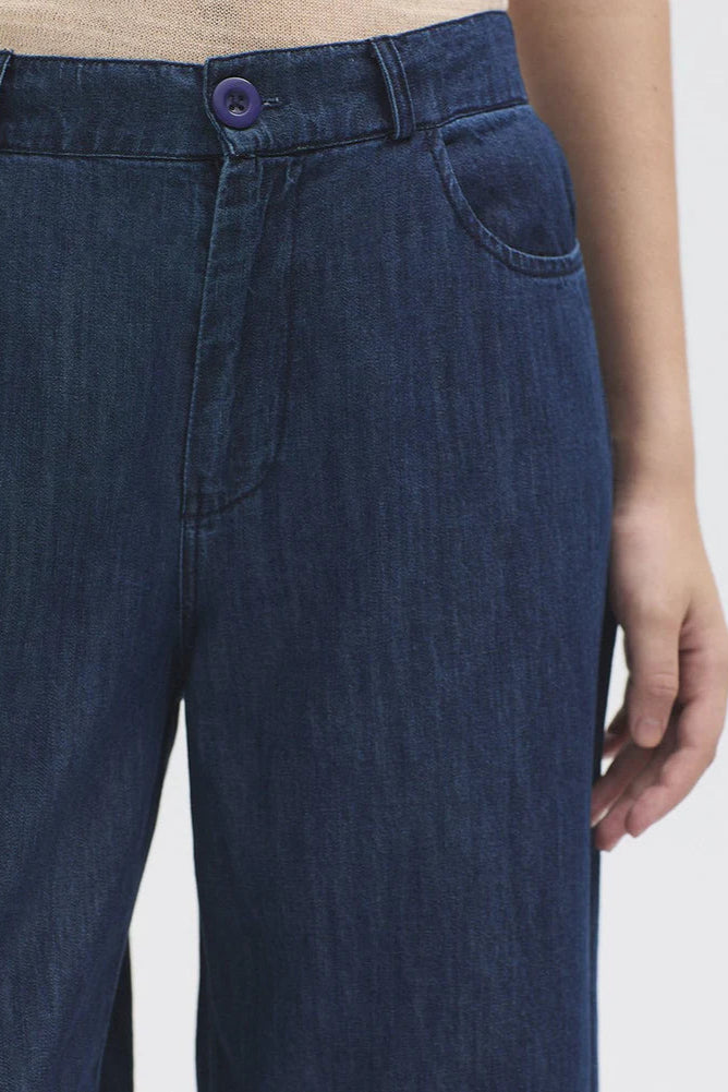 Model wearing wide leg denim jean with t shirt and trainers. 