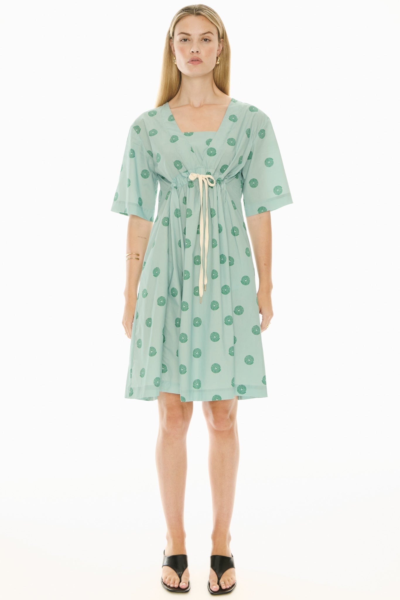 Woman wearing a green short sleeve midi patterned dress on a white background