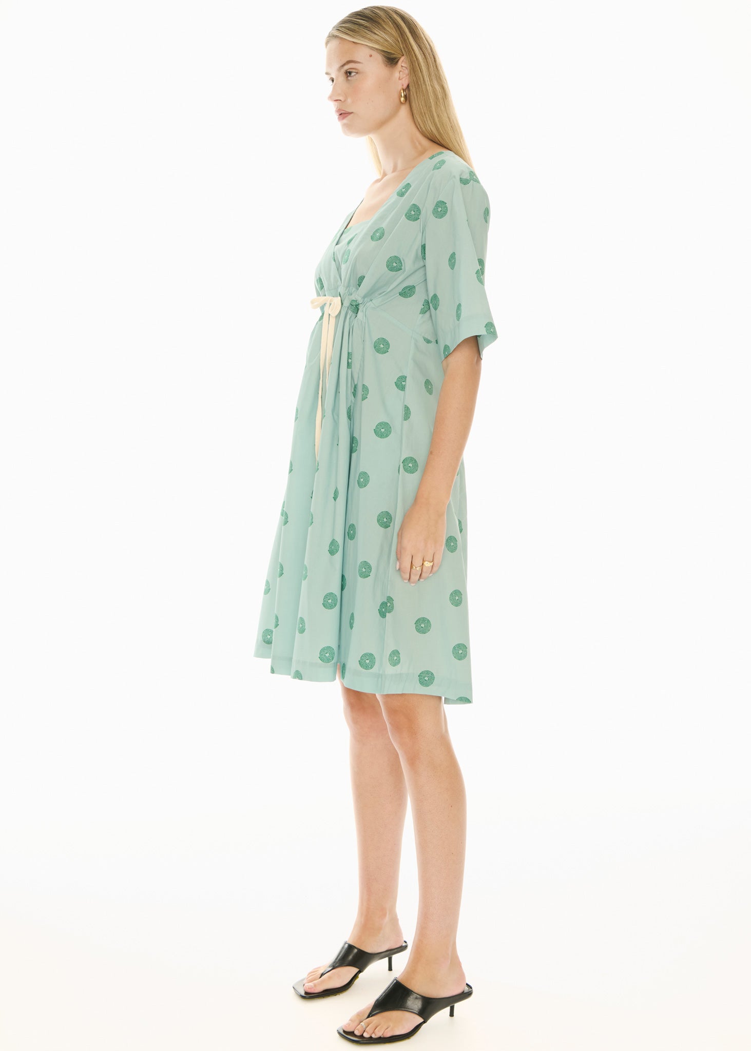 Woman wearing a green short sleeve midi patterned dress on a white background
