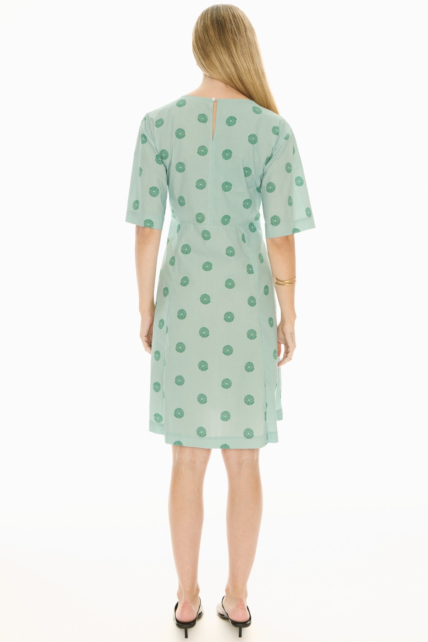 Woman wearing a green short sleeve midi patterned dress on a white background