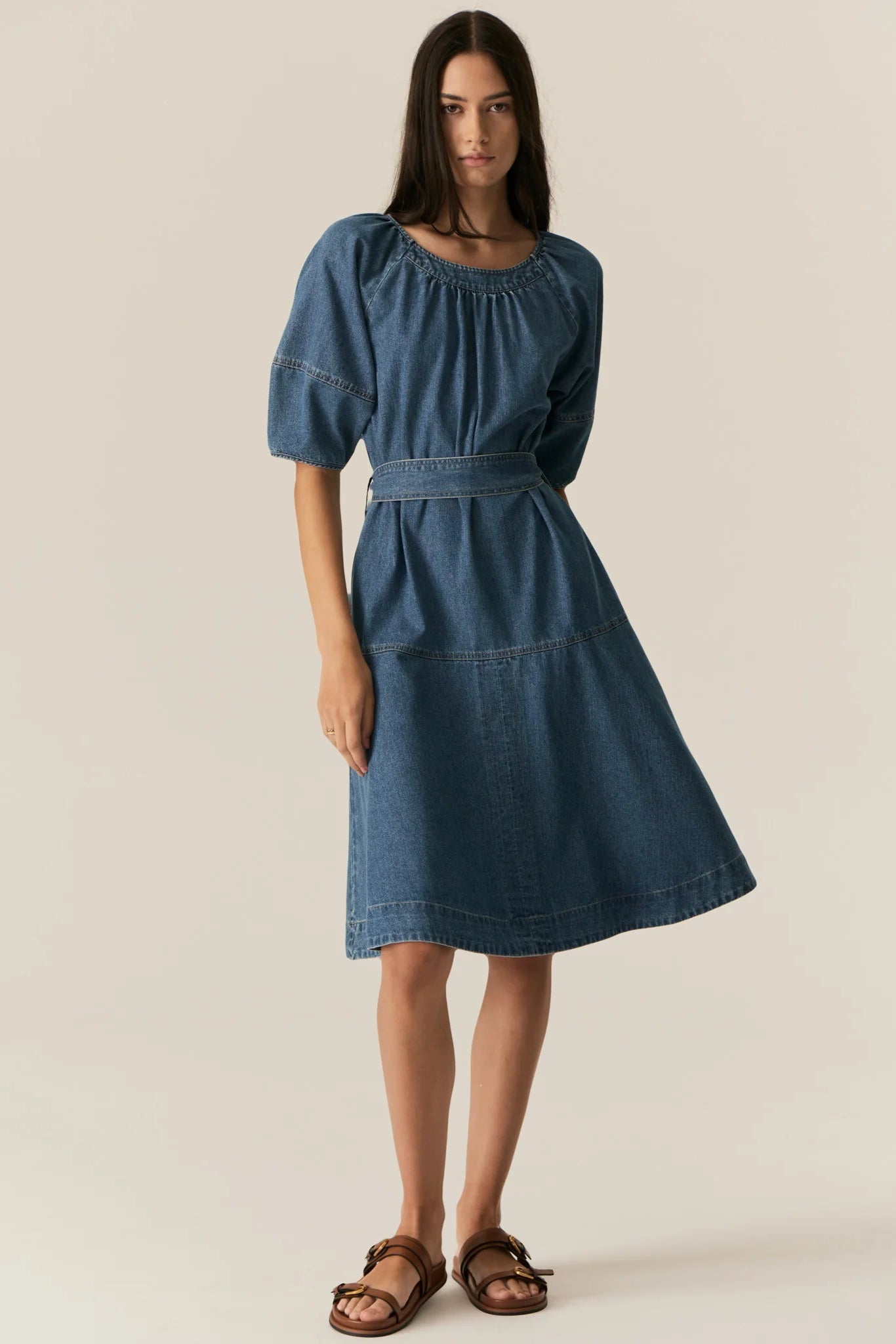 Woman wearing a blue denim short sleeve dress against a plain background
