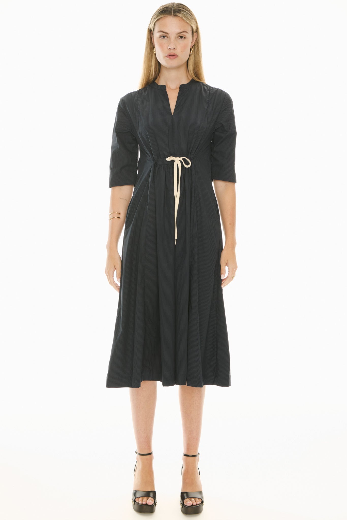 Woman wearing a ink blue short sleeve midi dress with a tie waist on a white background